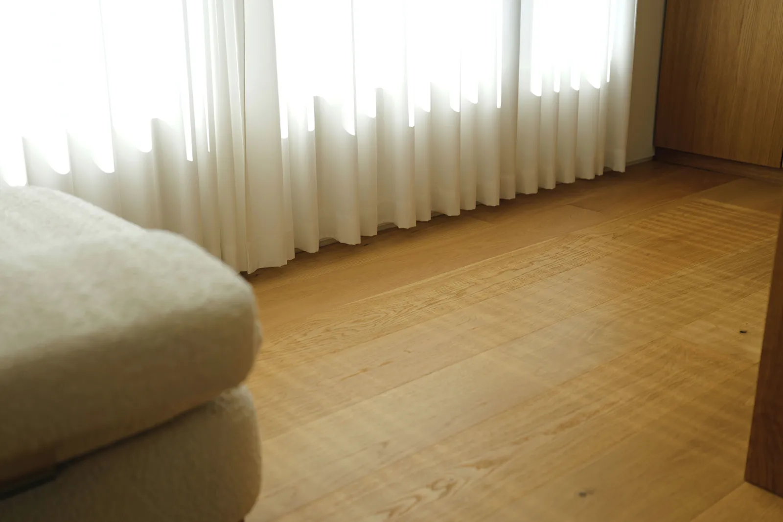 白いカーテン越しに光が差しこむ、あたたかな木の床